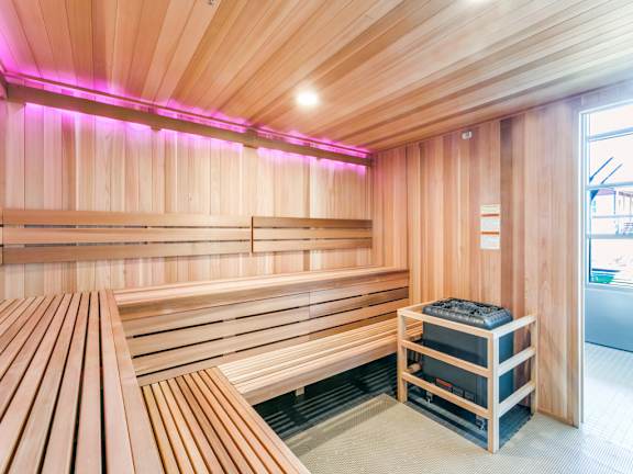 A sauna with wooden benches and a heater on the side.
