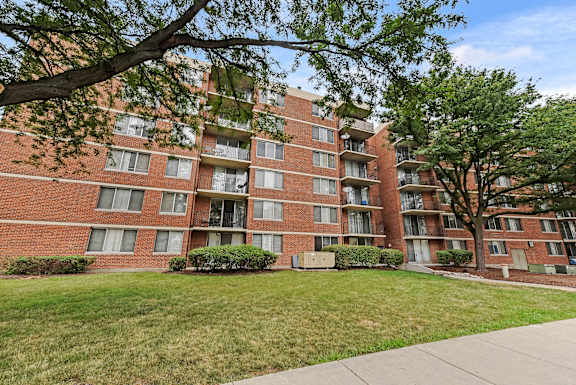 A red brick apartment building with a tree in front.