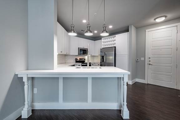 A kitchen with white cabinets and a white island with a counter.