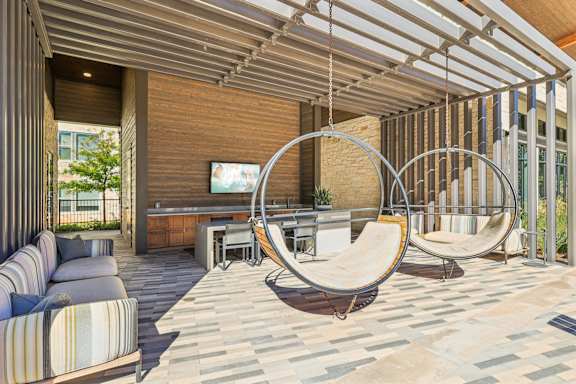 A modern outdoor living space with a hanging chair and a sofa.