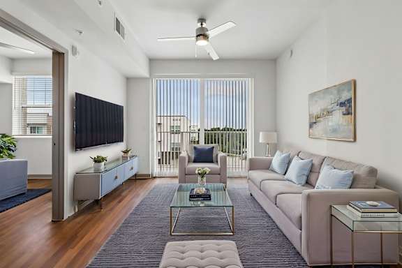 A modern living room with a large window and a ceiling fan.