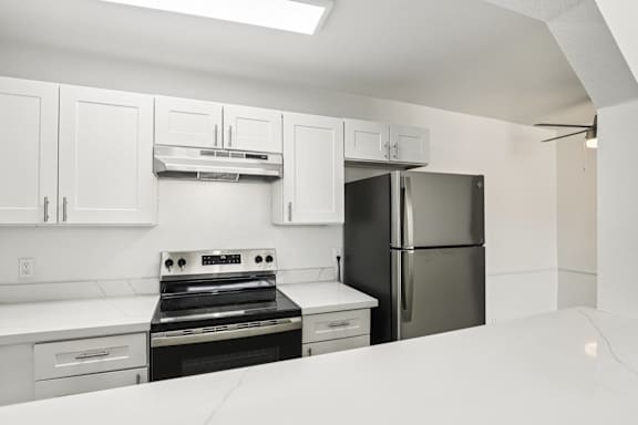 A kitchen with white cabinets and appliances.