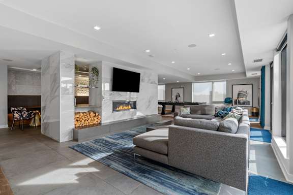 A modern living room with a grey couch and a fireplace.