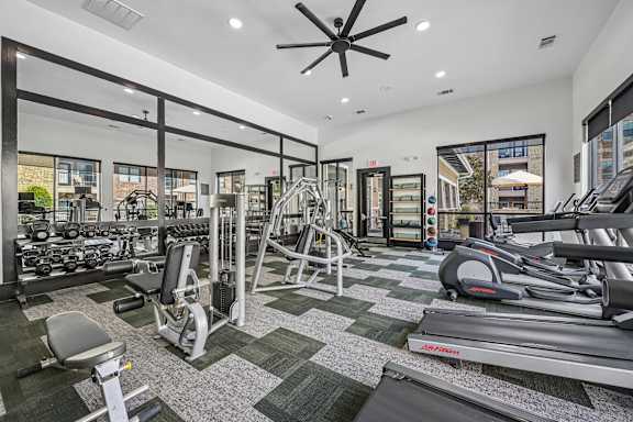 A gym with a variety of equipment including treadmills, weights, and exercise machines.