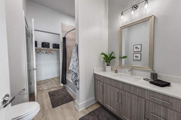 A bathroom with a toilet, sink, and mirror.