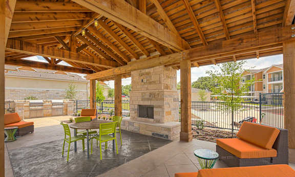 A patio with a fireplace and chairs.