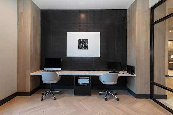 A black and white photo is on the wall above a desk with two chairs.