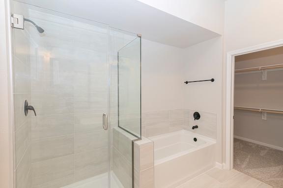 A white bathroom with a glass shower stall and a glass door.