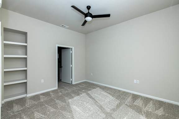 A room with a ceiling fan and a door.