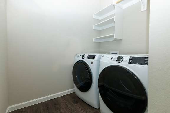 Two white front load washing machines in a laundry room.