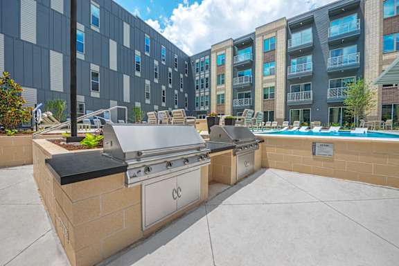 A modern outdoor kitchen area with a grill and sink.
