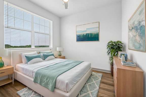 A bedroom with a bed, nightstand, and a painting on the wall.