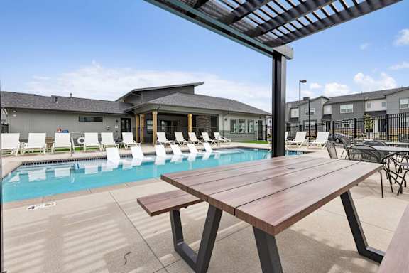 A wooden table is in the foreground of a pool area.