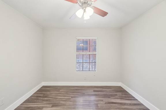 A room with a ceiling fan and a window with a view of a building outside.