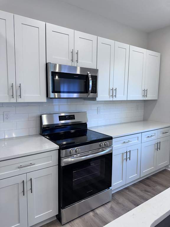 A kitchen with white cabinets and a black stove top oven.