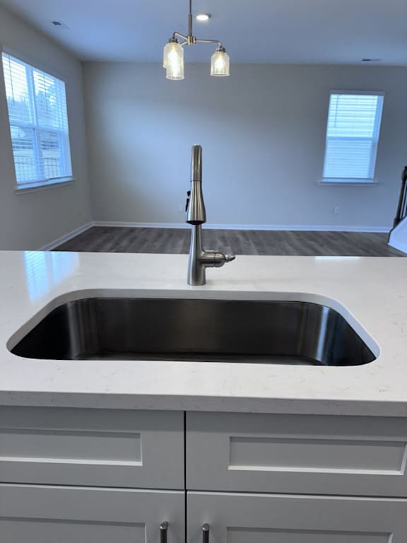 A modern kitchen with a stainless steel sink and white cabinets.