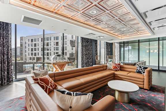 A living room with a large orange couch and a patterned rug.