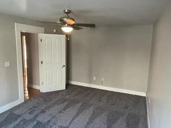 an empty living room with a ceiling fan and a door