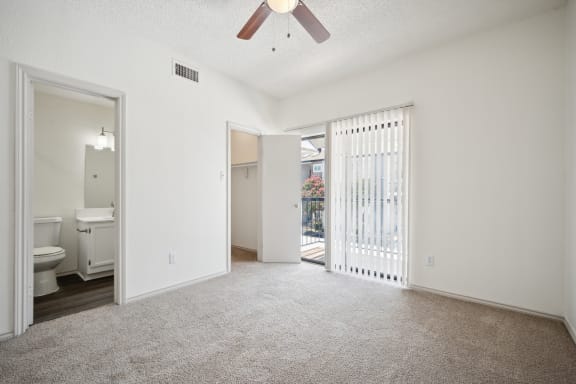 an empty living room with a sliding glass door to a bathroom