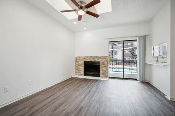 an empty living room with a fireplace and a ceiling fan