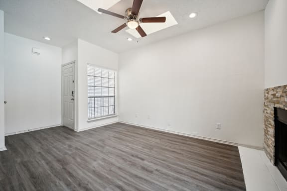 an empty living room with a ceiling fan and a fireplace