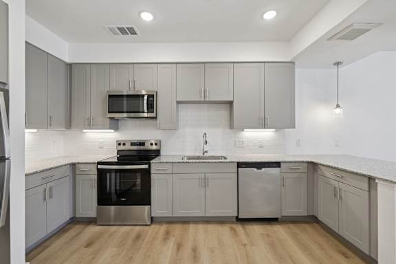 A modern kitchen with stainless steel appliances and wooden floors.