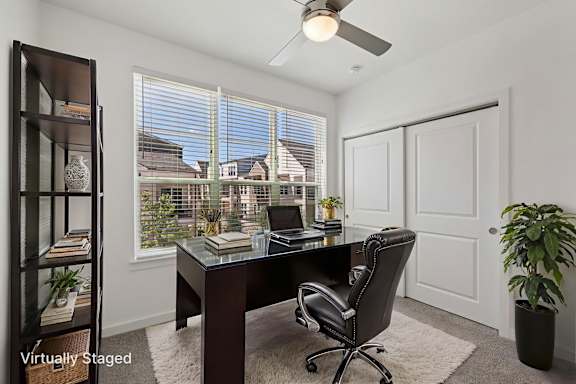 A room with a desk, chair, and a window with blinds.