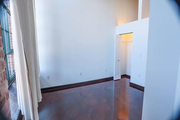 A room with a wooden floor and a doorway leading to another room.