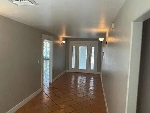 a empty living room with a tiled floor and a door