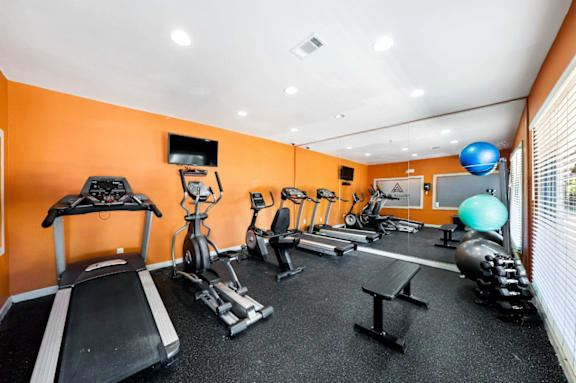 A gym with orange walls and a variety of exercise equipment.
