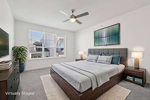 A bedroom with a bed, nightstands, and a ceiling fan.