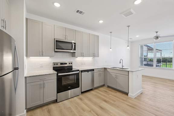 A modern kitchen with wooden floors and stainless steel appliances.