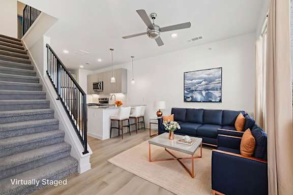 A living room with a staircase and a blue couch.