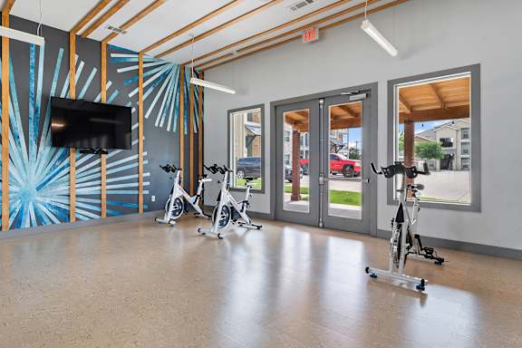 A room with exercise bikes and a television.