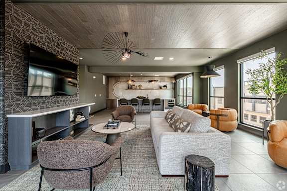 A modern living room with a grey sofa, a brown armchair, and a wooden coffee table.
