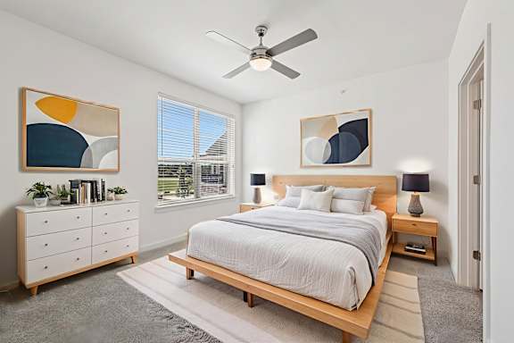 A bedroom with a bed, nightstand, and a ceiling fan.