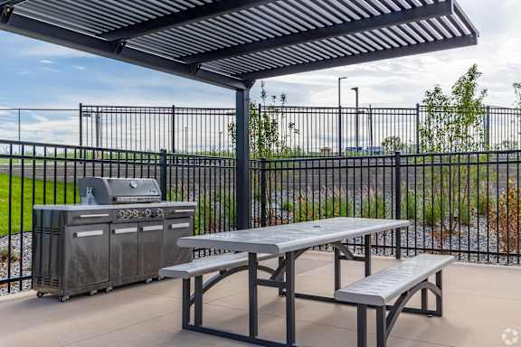 A picnic area with a grill and a table under a canopy.