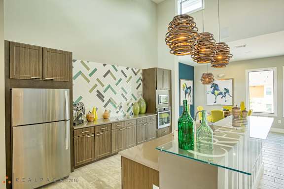 A modern kitchen with a glass counter top and wooden cabinets.