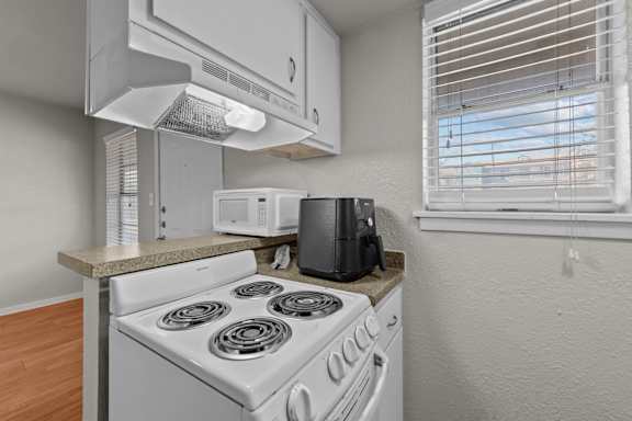 A white stove with a black toaster on a counter.