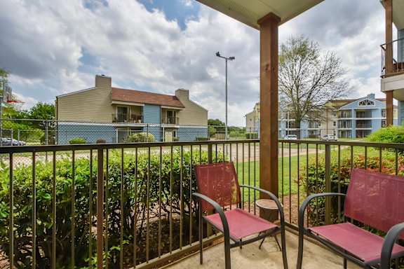 Two red chairs are on a patio.