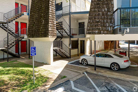 A white car is parked in a parking space with a handicap sign.