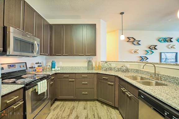 A kitchen with brown cabinets and a granite counter top.