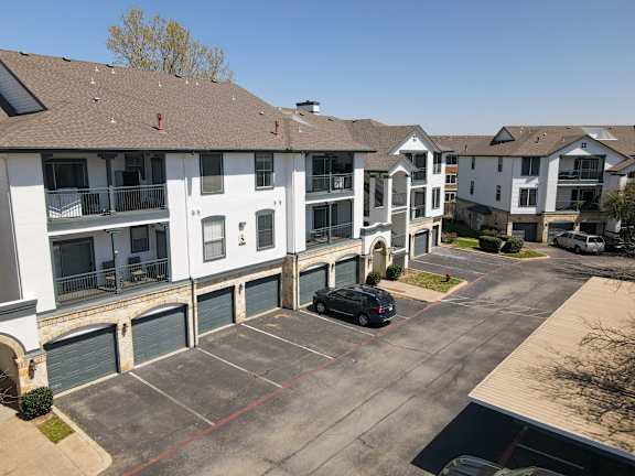 A black car is parked in a parking lot in front of a white building.