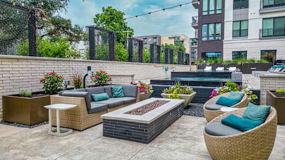 A patio with a table, chairs, and a fire pit.
