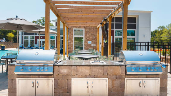 a patio with a barbecue grill and tables with umbrellas
