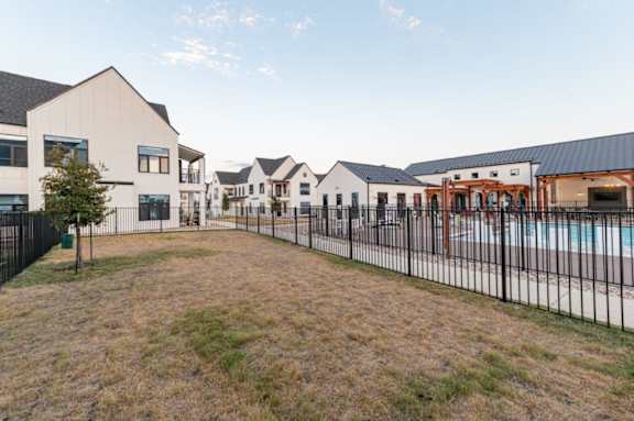 A large building complex with a pool and a fenced yard.