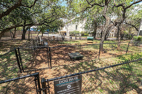 A dog park sign is displayed on a fence.