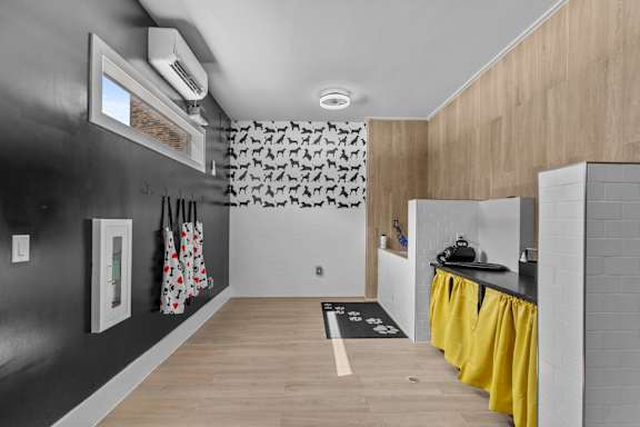A modern kitchen with a black wall and yellow curtains.