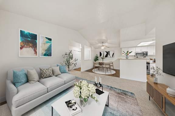 A living room with a grey couch and a coffee table with a vase of flowers on it.
