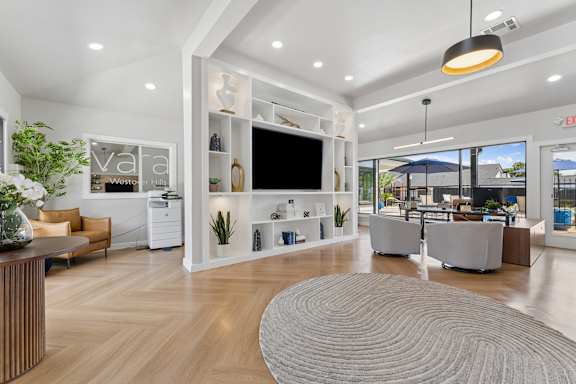 A modern office lobby with a reception desk, seating area, and a large window overlooking the outside.